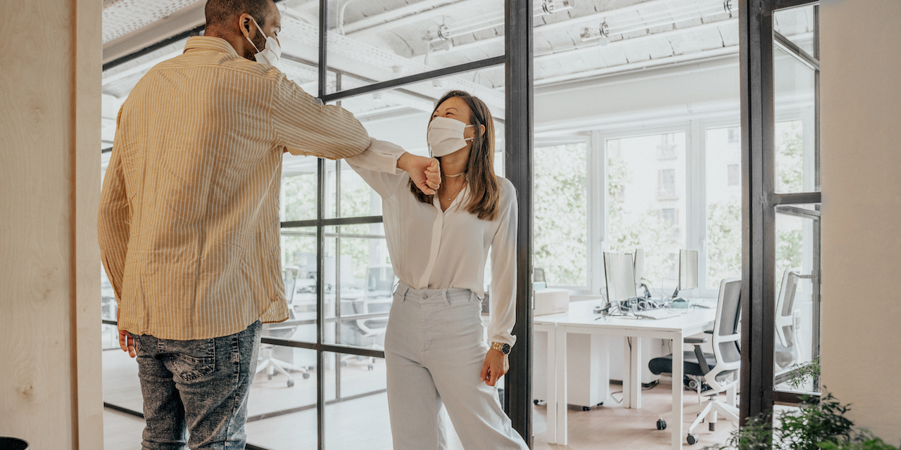 2 people wearing surgical masks in an office